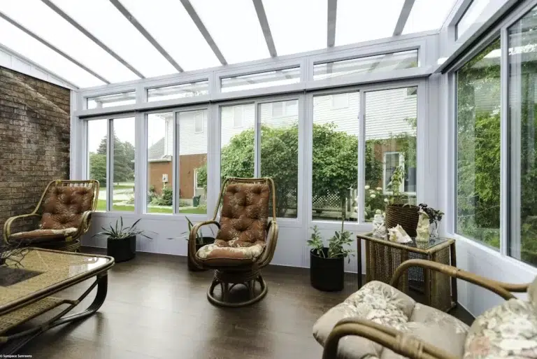 Sunroom interior featuring comfortable wicker seating, large glass windows, and a wooden floor, designed for enjoying outdoor views, promoting Sunspace By Sunrise Sunrooms' remodeling services in Scarborough, ME.