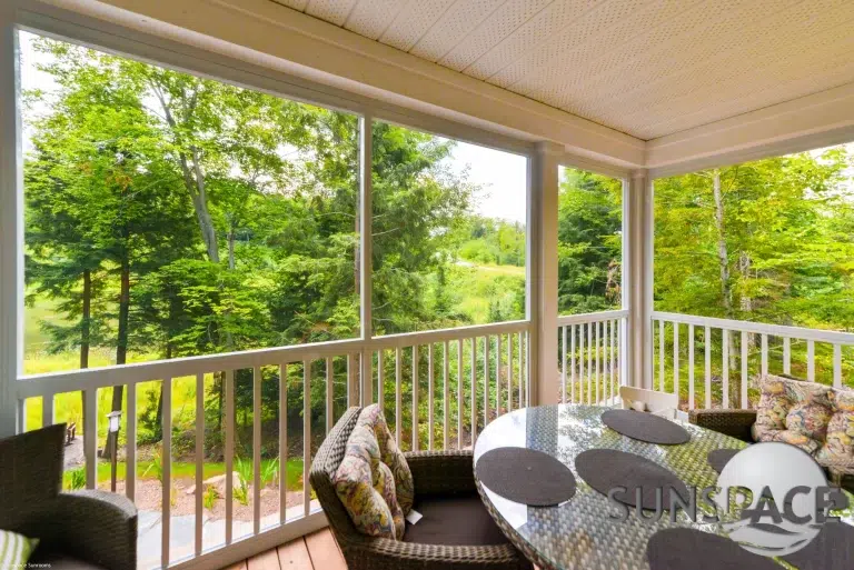 Sunspace sunroom featuring integrated railing, comfortable seating, and a scenic view of greenery, promoting outdoor living solutions.