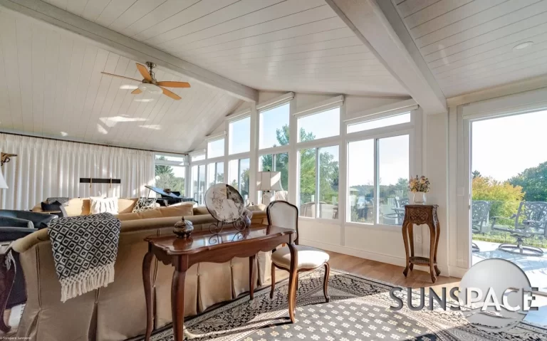 Bright, spacious Sunspace sunroom featuring large windows, a ceiling fan, elegant furnishings, and a cozy atmosphere, showcasing outdoor views and enhancing indoor living.