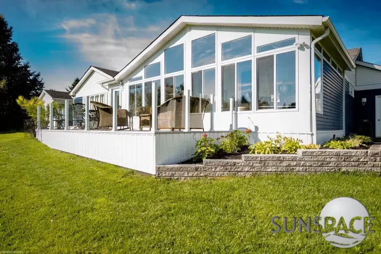 Sunspace sunroom with glass railing, featuring large windows, outdoor seating, and landscaped yard, promoting outdoor living solutions in Scarborough, ME.