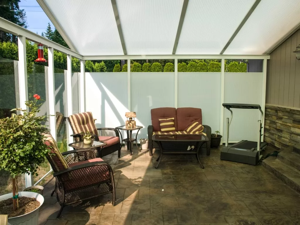 Sunroom interior featuring comfortable seating, decorative plants, and a treadmill, designed for outdoor living and relaxation.