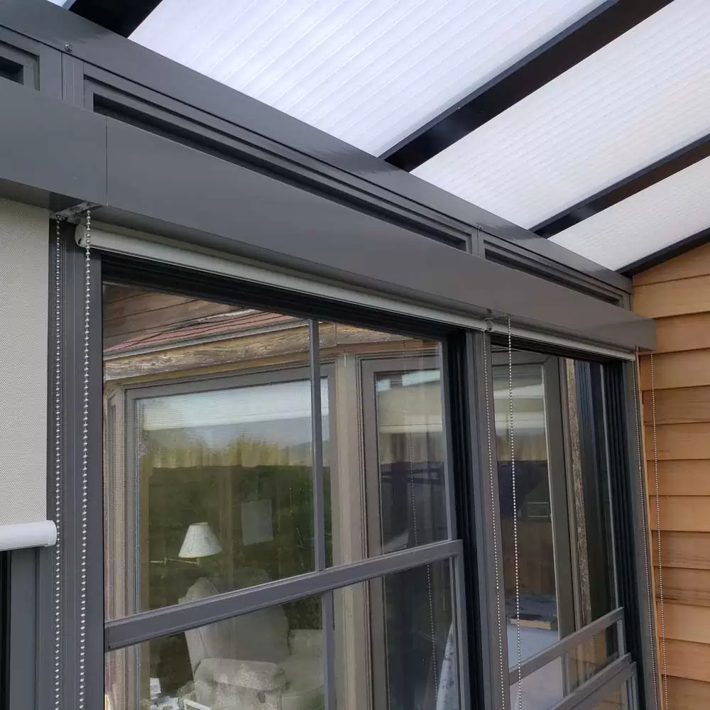 Close-up of a modern sunroom window with sleek gray framing and retractable screen, showcasing the durable design for enhanced outdoor living spaces.