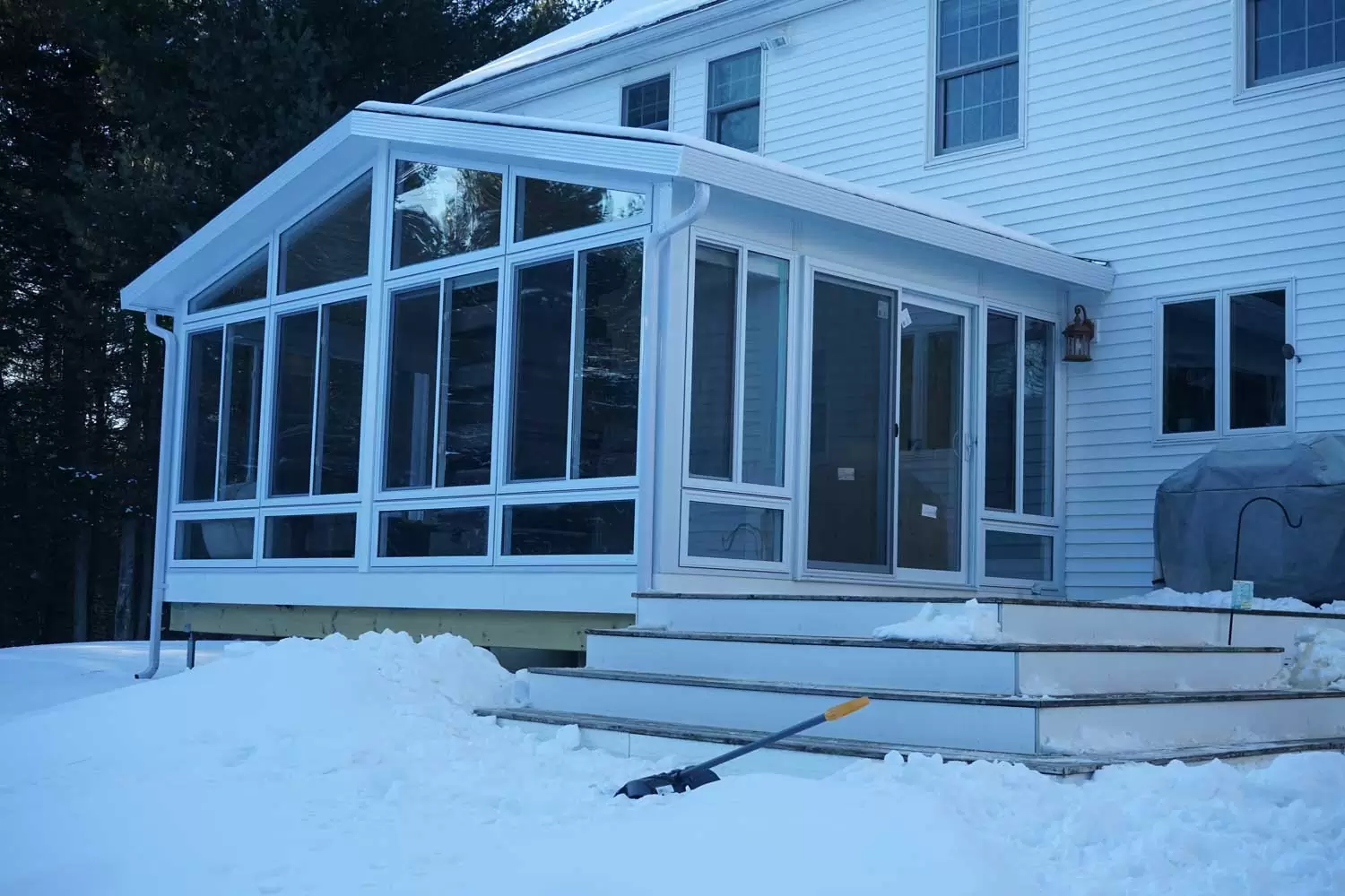Sunroom addition with large glass panels and white trim, surrounded by snow, showcasing a modern design for outdoor living in Scarborough, ME.