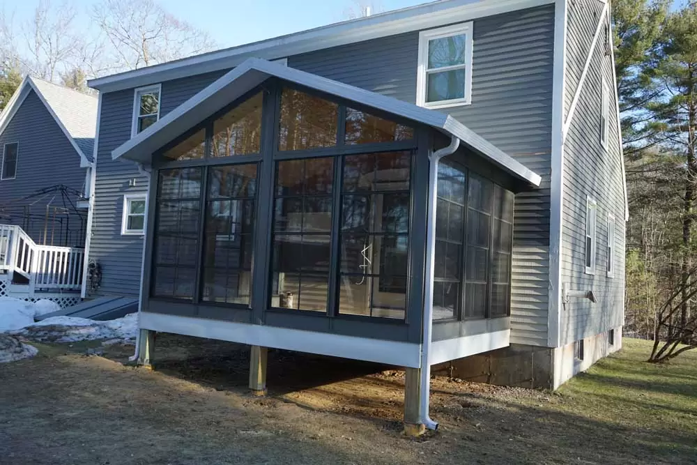 Custom sunroom addition with large windows and a peaked roof, enhancing outdoor living space at a residential property.