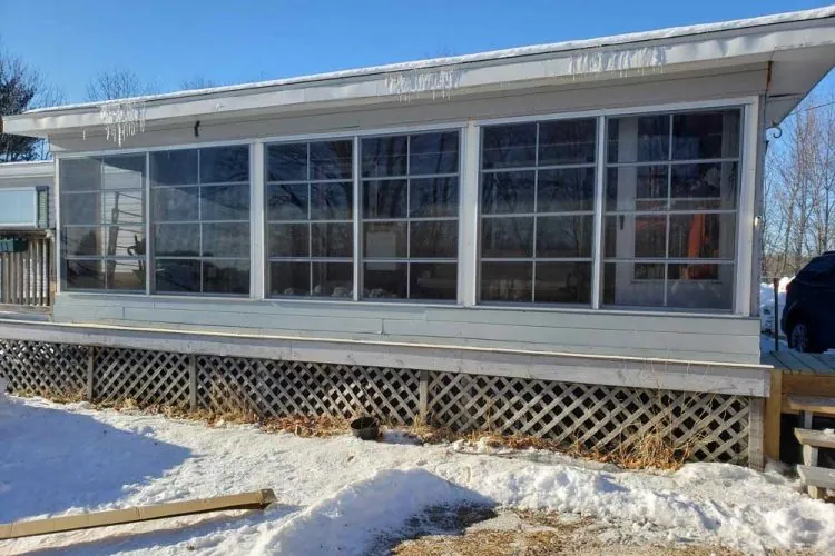 Porch enclosure by Sunspace featuring large windows, snow-covered ground, and a clear blue sky, showcasing an outdoor living space ideal for year-round enjoyment.